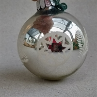 sølvfarvet glas julekugle med dekoration i hvidt stjerner og grangrene.